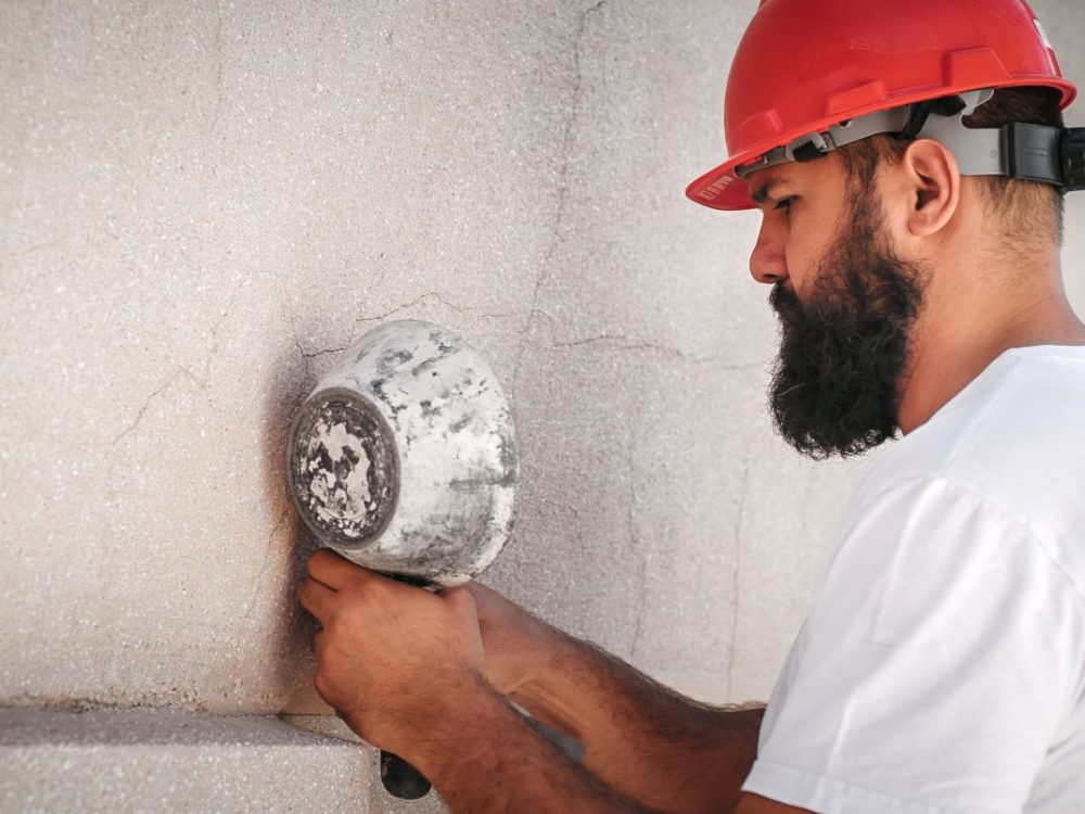 Construction mason worker plastering old building wall using cement plaster mix of cement and sand at the construction site