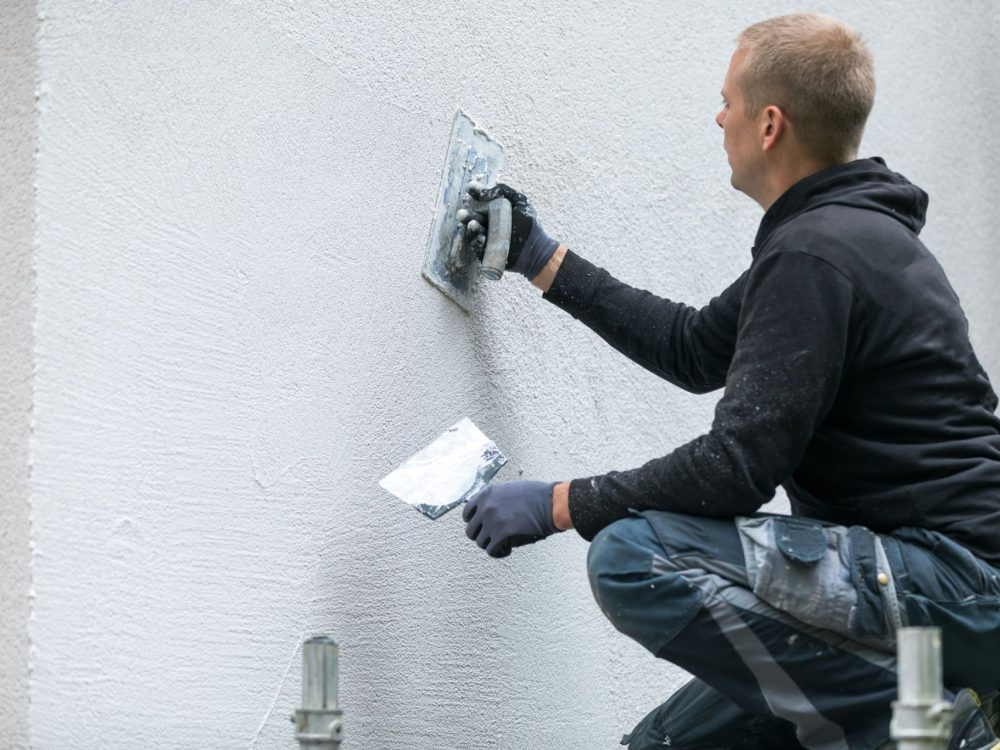 construction worker putting decorative plaster on house exterior